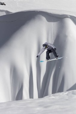 Karlı yamaçta uçan snowboardcu. Kış sporları, snowboard sporları.