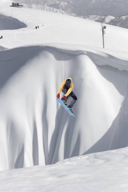 Karlı yamaçta uçan snowboardcu. Kış sporları, snowboard sporları.