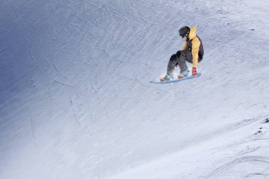 Karlı yamaçta uçan snowboardcu. Kış sporları, snowboard sporları.