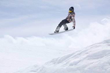 Karlı yamaçta uçan snowboardcu. Kış sporları, snowboard sporları.