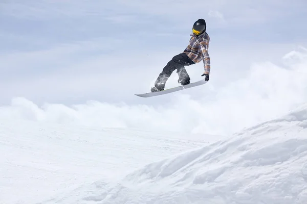 スノーボーダーは雪の斜面を背景に空を飛んでいます。極端な冬のスポーツ、スノーボード. — ストック写真