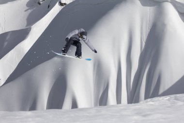 Karlı yamaçta uçan snowboardcu. Kış sporları, snowboard sporları.