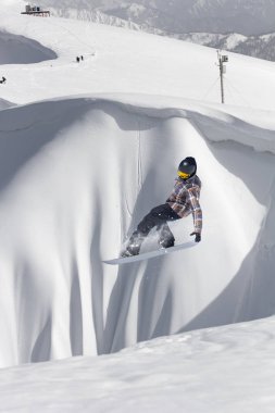 Karlı yamaçta uçan snowboardcu. Kış sporları, snowboard sporları.