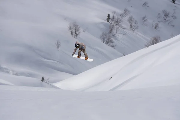 Snowboardzista lecący na tle śnieżnego stoku. Sporty ekstremalne zimowe, snowboarding. — Zdjęcie stockowe