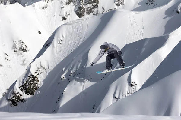 Snowboarder volando en el fondo de la pendiente nevada. Deportes extremos de invierno, snowboard. —  Fotos de Stock