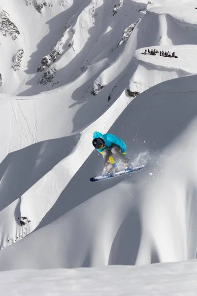 Snowboarder voando no fundo da encosta nevada. Esportes de inverno extremos, snowboard. — Fotografia de Stock