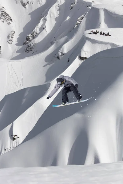 Snowboardåkare flyger på bakgrunden av snöig sluttning. Extrema vintersporter, snowboard. — Stockfoto