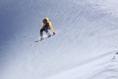 Karlı yamaçta uçan snowboardcu. Kış sporları, snowboard sporları.
