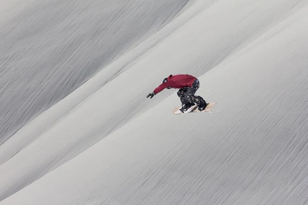 Snowboarder volando en el fondo de la pendiente nevada. Deportes extremos de invierno, snowboard. — Foto de Stock