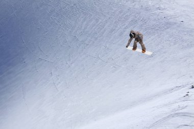 Karlı yamaçta uçan snowboardcu. Aşırı kış sporları, snowboard sporları. Boşluğu kopyala.
