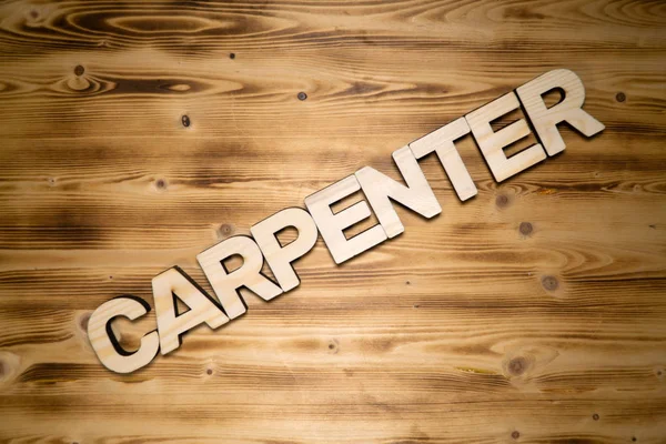 CARPENTER palavra feita de letras de bloco de madeira na placa de madeira . — Fotografia de Stock