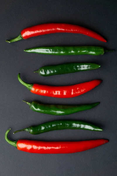 Pimientos chile verde y rojo sobre fondo negro vista superior. Comida picante caliente . —  Fotos de Stock