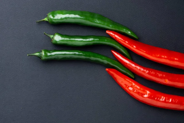 绿色和红色辣椒在黑色背景顶部的看法。热辣食品. — 图库照片