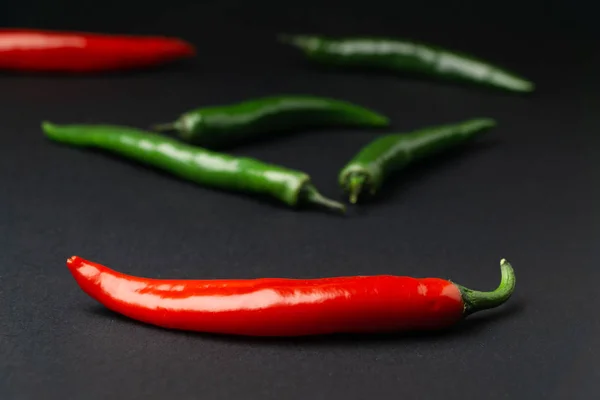 Zielona i czerwona papryka chili na czarnym tle. Hot spicy żywność. — Zdjęcie stockowe