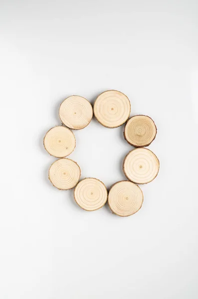 Circle of pine tree cross-sections with annual rings on white background. Lumber piece close-up, top view.