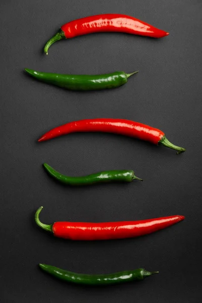 绿色和红色辣椒在黑色背景顶部的看法。热辣食品. — 图库照片