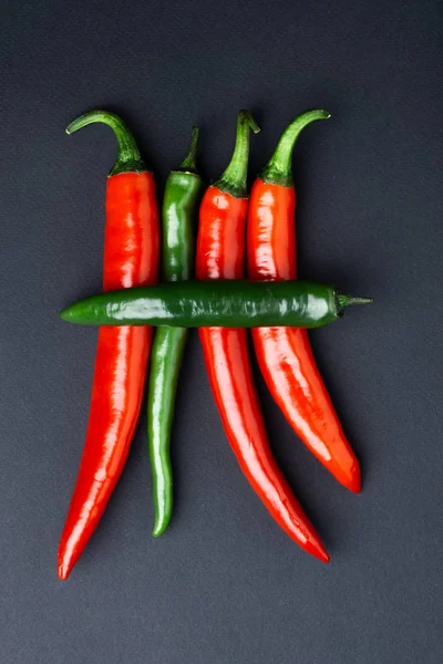 Pimientos chile verde y rojo sobre fondo negro vista superior. Comida picante caliente . —  Fotos de Stock