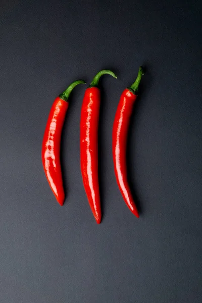 Κάτοψη του πράσινες και κόκκινες πιπεριές τσίλι σε μαύρο φόντο. Καυτά πικάντικα τρόφιμα. — Φωτογραφία Αρχείου