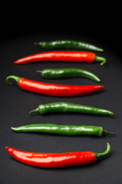 Chiles verdes y rojos sobre fondo negro. Comida picante caliente . —  Fotos de Stock