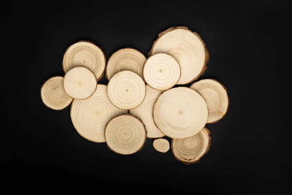 Pine tree cross-sections with annual rings on black background. Lumber piece close-up, top view. — Stock Photo, Image