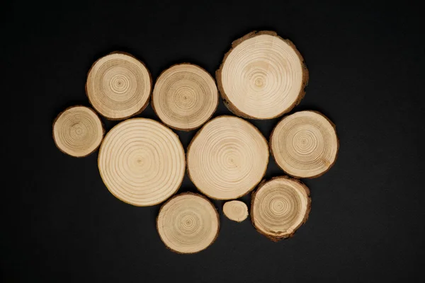 Secções transversais de pinheiro com anéis anuais sobre fundo preto. Peça de madeira close-up, vista superior . — Fotografia de Stock