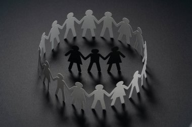 Üç insan kağıt rakamlar karanlık yüzey üzerinde el ele tutuşarak kağıt insanların daire çevrili. Bulling, segregasyon, çatışma kavramı.