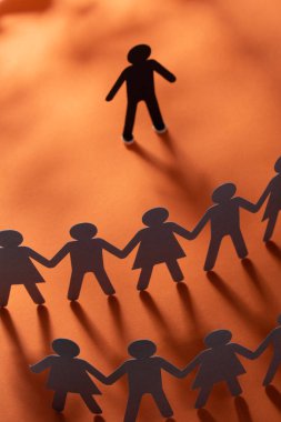 Kağıt insan figürü ayakta kırmızı yüzey üzerinde el ele tutuşarak kağıt insanların önünde. Bulling, segregasyon, çatışma kavramı.