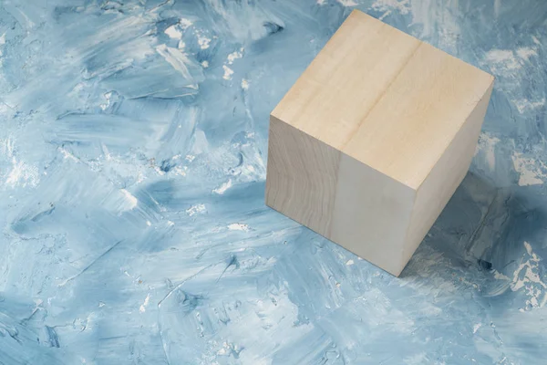 Bright wood cube on white and blue painting surface. Wooden cube and a piece of fine art studio shot.