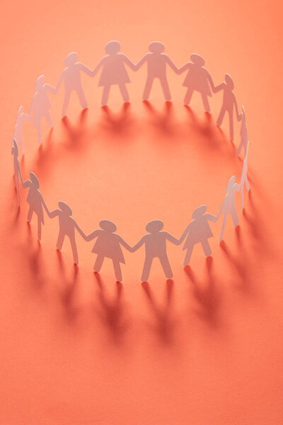 Круг бумажных людей, держащихся за руки на розовой поверхности. Общество, концепция профсоюза. Общество и поддержка.