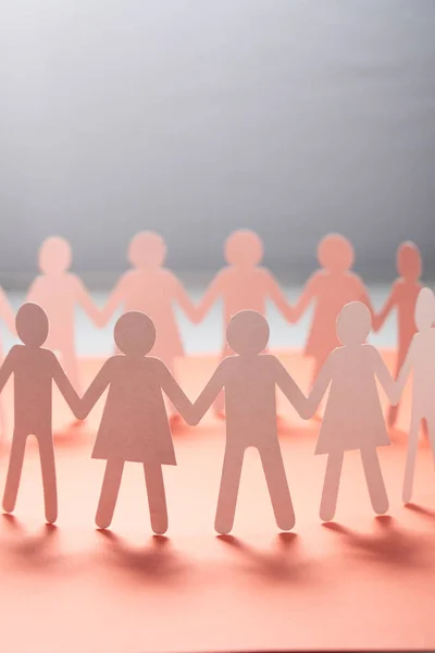 Kruh papírových lidí držících se za ruce na růžovém povrchu. Komunitní, odborová koncepce. Společnost a podpora. — Stock fotografie