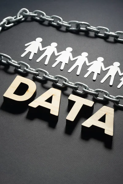 DATA letters in front of human paper figures and metal chain on black background. Personal data protection concept.