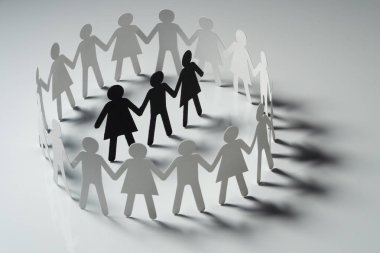 Üç insan kağıt rakamlar beyaz yüzey üzerinde el ele tutuşarak kağıt insanların daire çevrili. Bulling, segregasyon, çatışma kavramı.