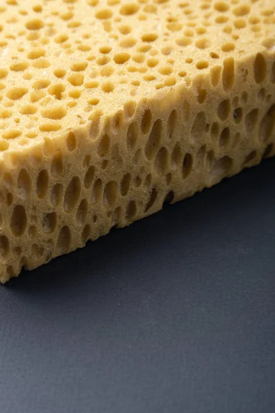 Close up view of cleaning sponge, mesh structure pattern on black surface. Yellow sponge close-up. — Stock Photo, Image