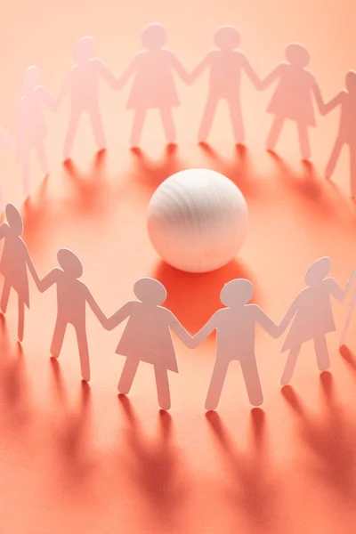 Circle of paper people holding hands in front of white ball. Brotherhood, cult concept. — Stock Photo, Image