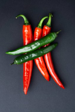 Siyah zemin üzerine yeşil ve kırmızı biber görünümü top. Baharatlı yemekler için.