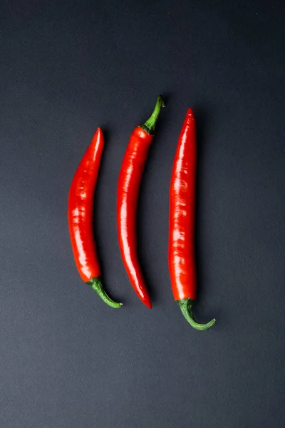 Κάτοψη του πράσινες και κόκκινες πιπεριές τσίλι σε μαύρο φόντο. Καυτά πικάντικα τρόφιμα. — Φωτογραφία Αρχείου