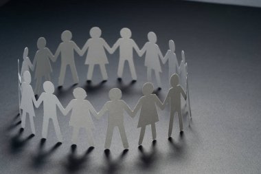 Karanlık yüzey üzerinde el ele tutuşarak kağıt insanların daire. Topluluk, sendika kavramı. Toplum ve destek.
