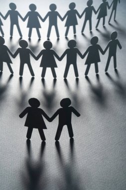 Siyah kağıt bir kalabalığın önünde bir çift beyaz yüzey üzerinde el ele tutuşarak kağıt insan figürü. Toplumsal hareket, liderlik, protesto kavramı.