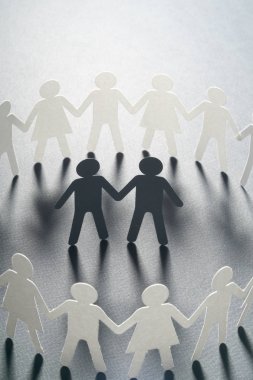 Kağıt beyaz yüzey üzerinde el ele tutuşarak kağıt insanların daire çevrili birkaç erkek figürü. Bulling, azınlıklar, çatışma kavramı.