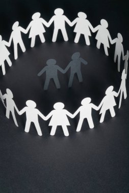 Karanlık yüzey üzerinde el ele tutuşarak kağıt insanların daire çevrili bir erkek kaç kağıt rakam. Bulling, azınlıklar, çatışma kavramı.