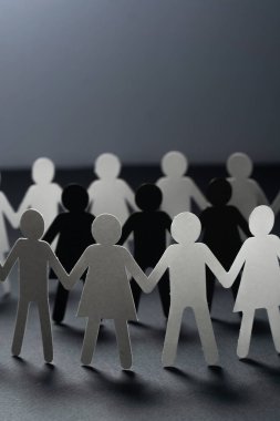 Üç insan kağıt rakamlar karanlık yüzey üzerinde el ele tutuşarak kağıt insanların daire çevrili. Bulling, segregasyon, çatışma kavramı.