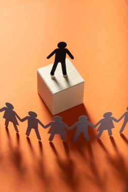 Kağıt lider figürü önünde kırmızı yüzey üzerinde el ele tutuşarak kağıt insanlar. Lider, politikacı, patron.