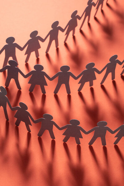 Бумажные люди держатся за руки на красной поверхности. Общество, концепция профсоюза. Общество и поддержка
.