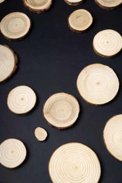 Pine tree cross-sections with annual rings on plane black surface. Lumber piece close-up.