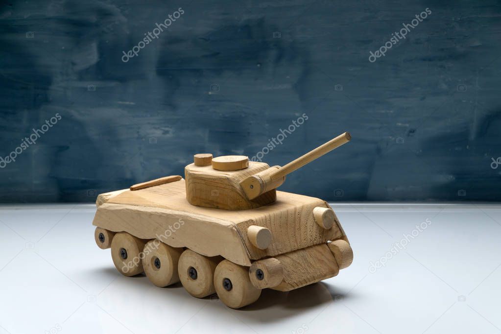 Wood tank on blue painted background. Wooden toy tank studio shot.