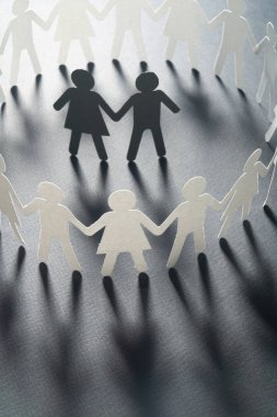 Beyaz yüzey üzerinde el ele tutuşarak kağıt insanların daire çevrili bir kaç kağıt rakam. Bulling, azınlıklar, çatışma kavramı.