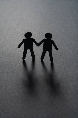 Siyah kağıt şekil bir erkek çift Holding gri yüzeyinde eller. Eşcinsel evlilik, çeşitlilik, azınlık kavramı.