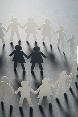 Kağıt şekil kadın çift gri yüzey üzerinde el ele tutuşarak kağıt insanların daire çevrili. Bulling, azınlıklar, çatışma kavramı.