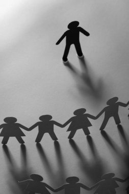Kağıt insan figürü ayakta beyaz yüzey üzerinde el ele tutuşarak kağıt insanların önünde. Bulling, segregasyon, çatışma kavramı.
