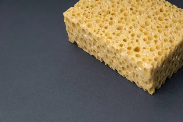 Close up view of cleaning sponge, mesh structure pattern on black surface. Yellow sponge close-up. — Stock Photo, Image